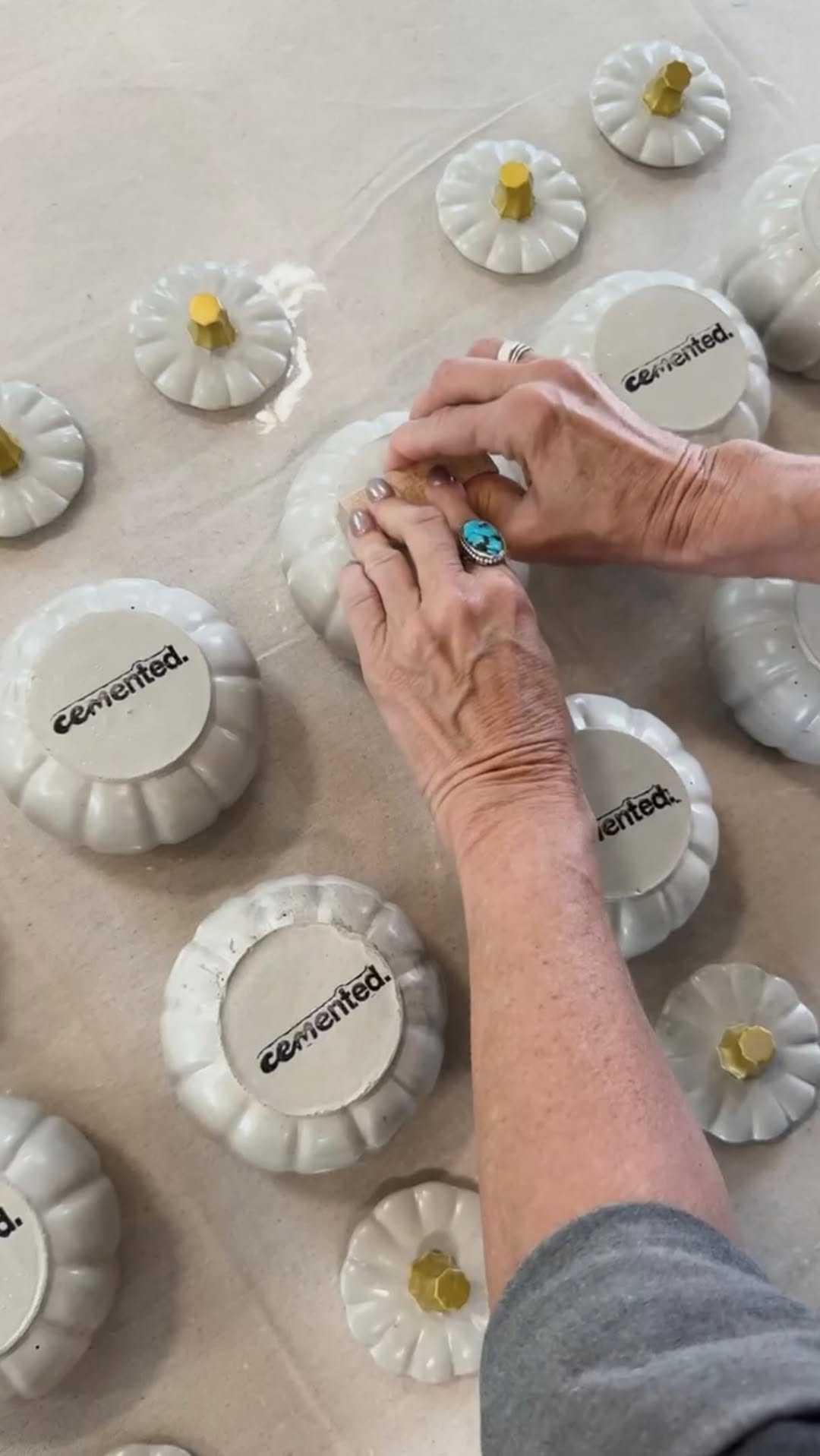 Hands crafting cement pumpkins at a Flowering Cottage workshop