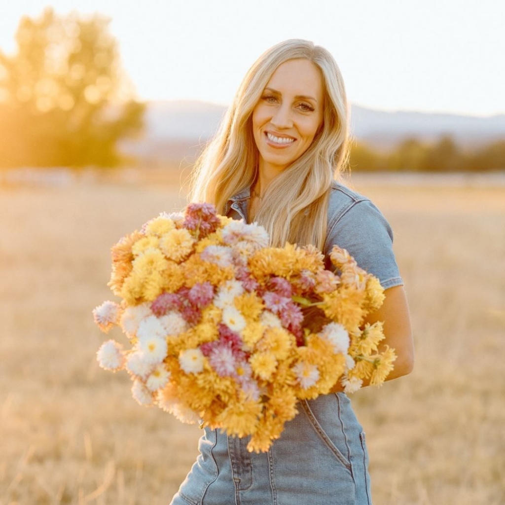 Jennica Burnett holding an armful of fresh-cut flowers in the field